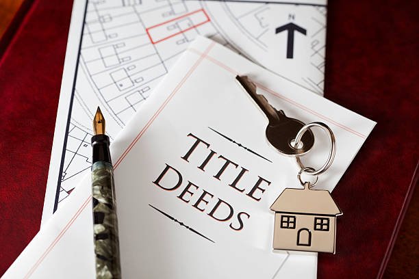 Title deeds resting on a desk alongside a key and a pen